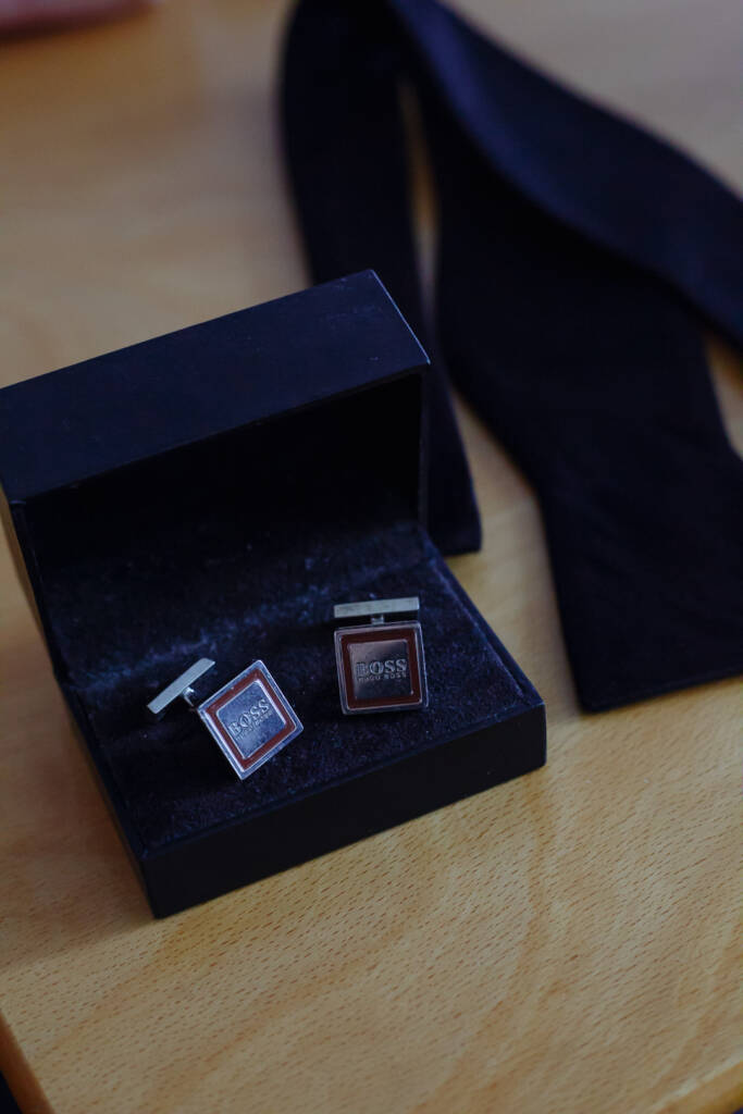 Square silver cufflinks sit boxed beside the untied velvet bow