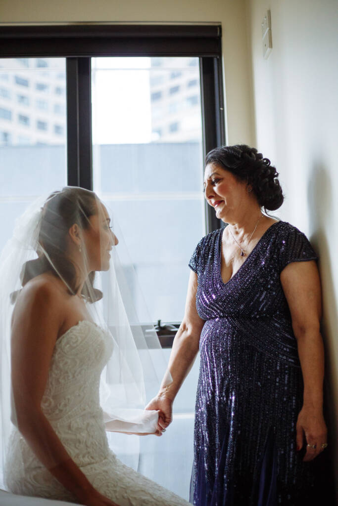 Hands held, a long look between the bride and the woman in sequinned navy through the tulle.