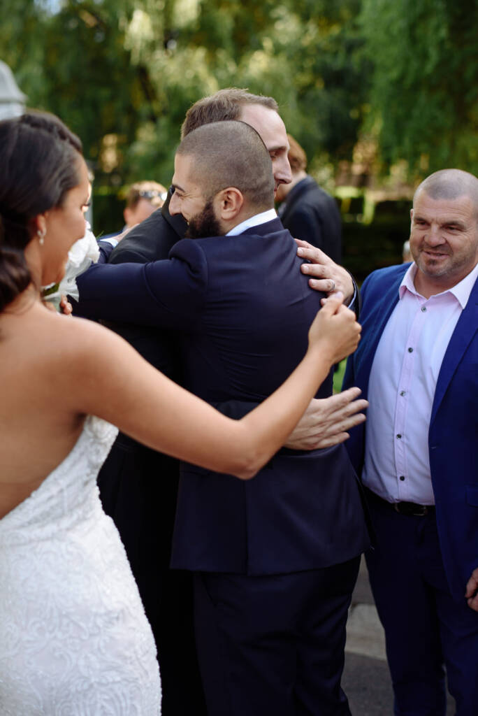 The groom disappears into a round of bear hugs