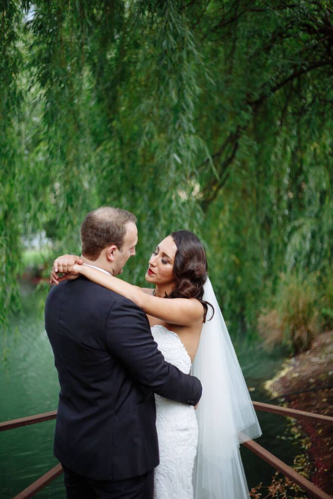 The bride's arms looped around the groom's neck on the little iron bridge beneath the willows.