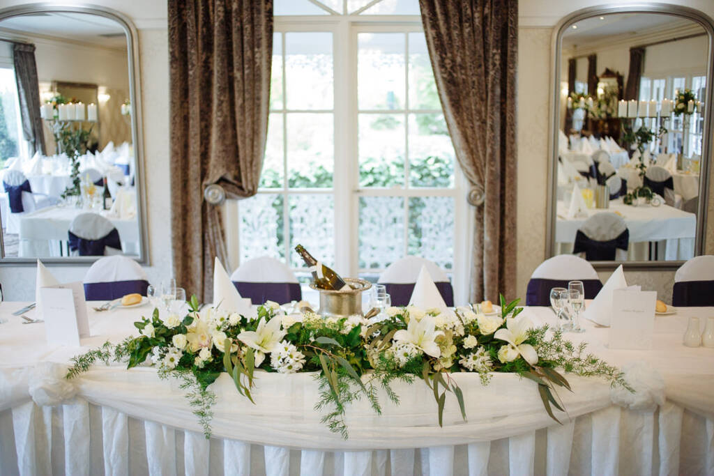 Lilies and eucalyptus spill along the skirted bridal table