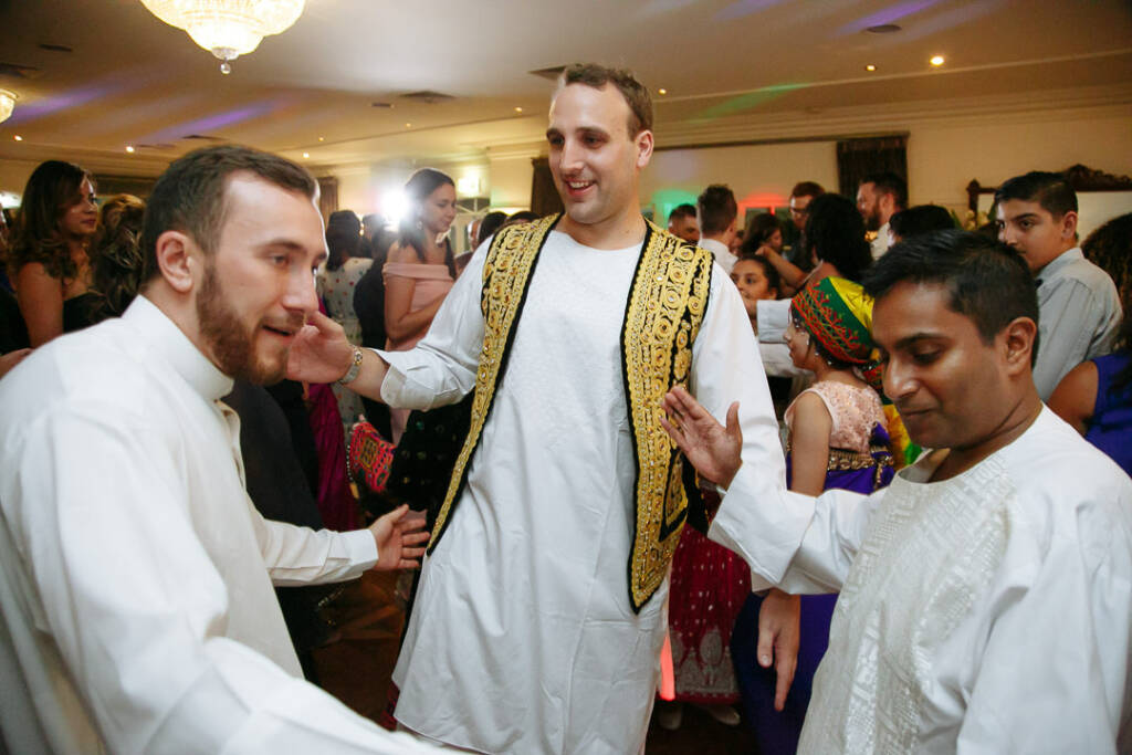White tunics gather as the groomsmen join the groom in his gold embroidered vest on the floor.