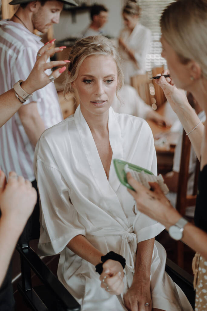 Emma sits in a satin robe while her hair and makeup are finished.
