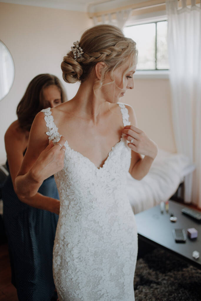 A guest adjusts the lace strap of Emma’s wedding gown.
