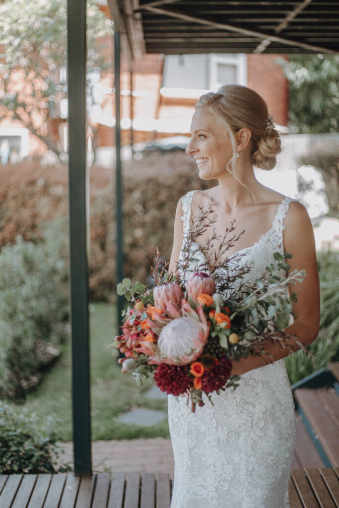 Emma smiles in profile above her bridal bouquet.