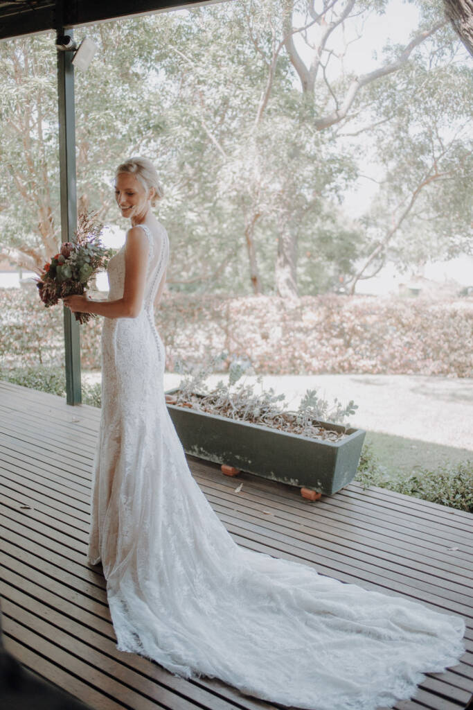 Emma looks back as her lace train spreads across the covered deck of a private home in Allambie Heights.