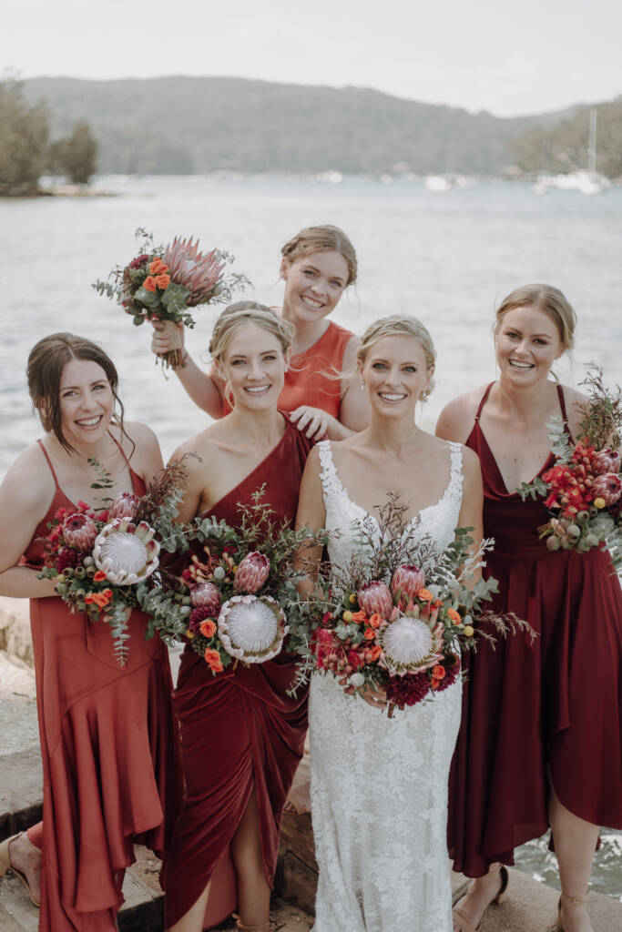 Emma poses with four attendants in rust and burgundy dresses near BYRA.