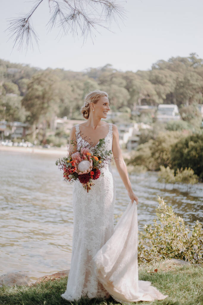 Emma lifts her train for a bridal portrait on the grass near Bayview Yacht Racing Association.