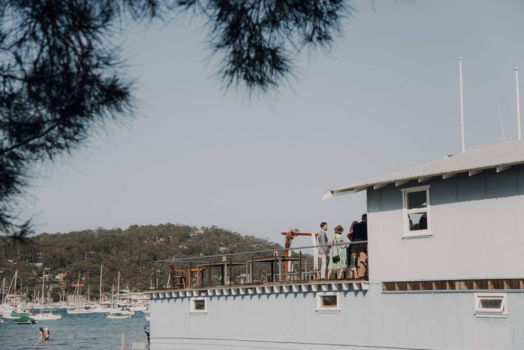 Guests gather on BYRA’s deck for a waterside wedding ceremony on the Northern Beaches.
