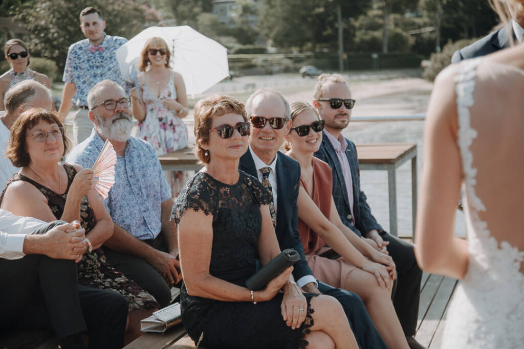 A wedding guest holds a folding fan among the seated guests at Bayview Yacht Club.