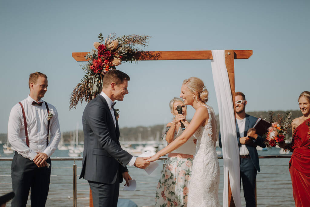 Emma laughs while holding Sean’s hands as a microphone is held towards her.