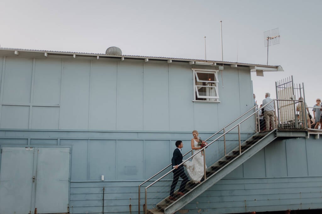 Emma and Sean stand on the outside staircase of Bayview Yacht Club’s pale-blue clubhouse.
