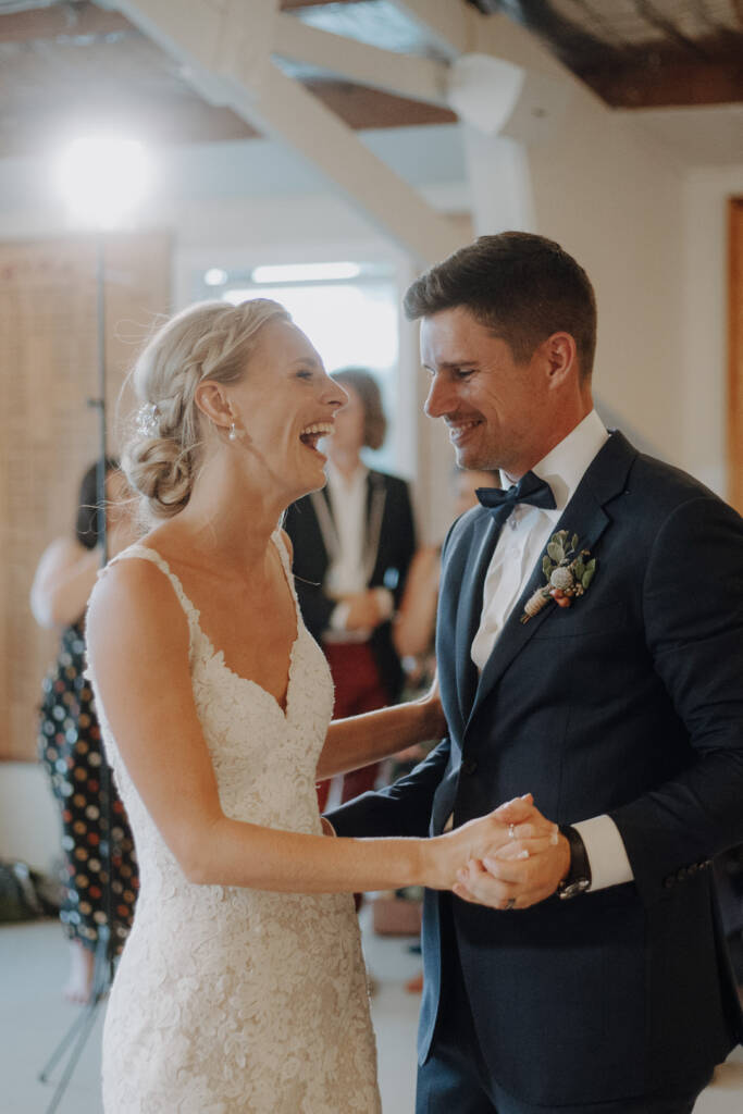 Emma and Sean smile at each other with hands joined during their wedding dance at BYRA.