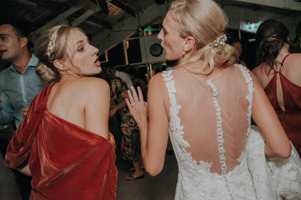 Emma and an attendant in a rust-coloured dress dance facing each other.