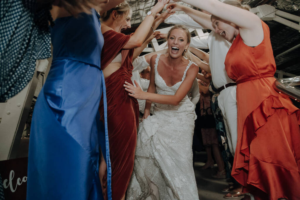 Emma ducks beneath a tunnel of guests’ raised arms inside Bayview Yacht Club.
