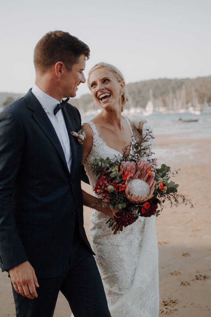 Emma laughs up at Sean during their beach wedding portraits near Bayview Yacht Club.