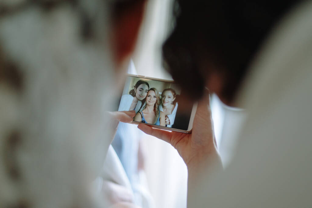 A phone captures a cheerful bridal party selfie during Becky’s wedding preparations.