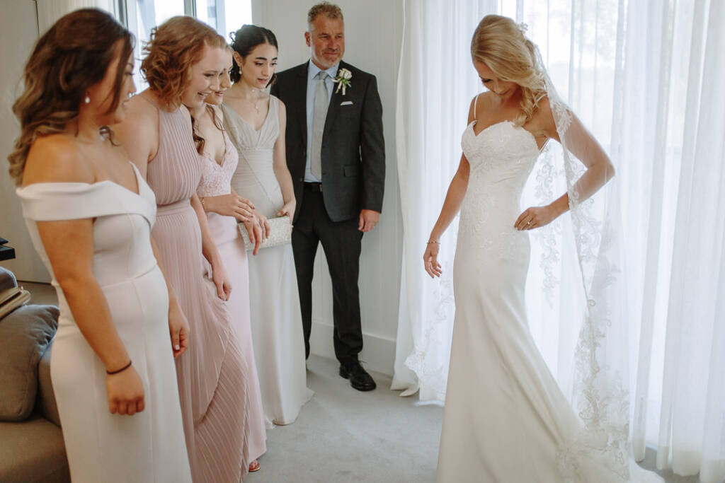 Becky shares a joyful reveal with her bridesmaids and a loved one after getting dressed.