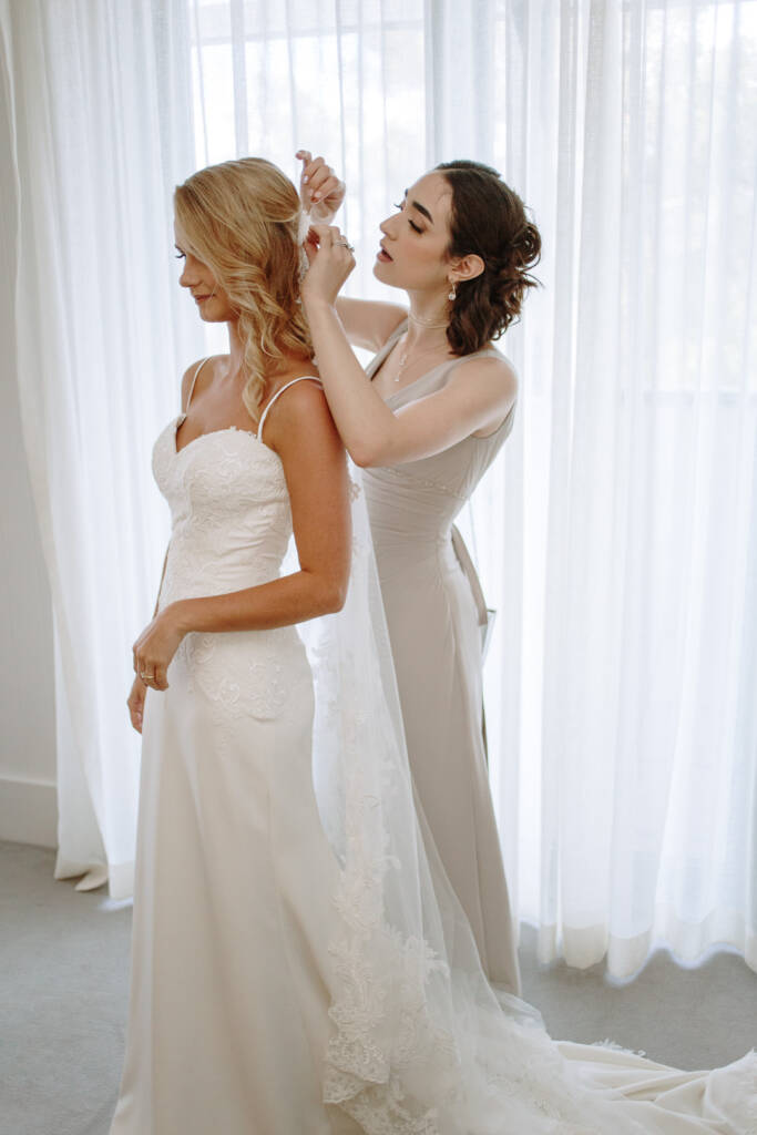 A helper fastens Becky's lace-edged wedding veil above her loose curls.