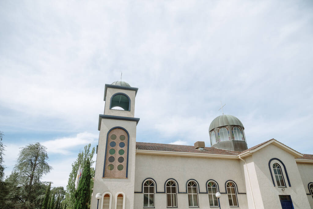 Dome and bell tower of St Nicholas Greek Orthodox Church, Canberra beneath a cloudy sky.