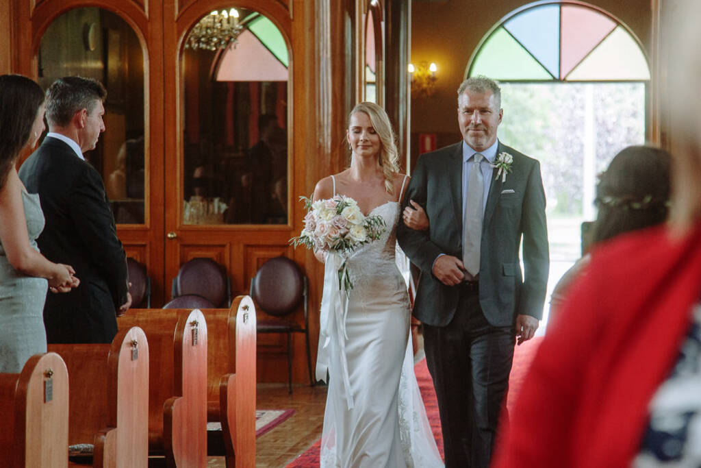 Becky enters St Nicholas Canberra with a male wedding companion.