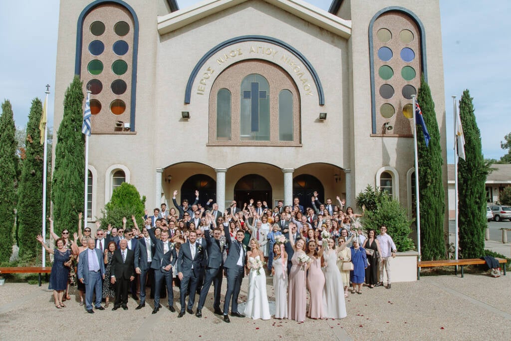 Becky, George and their guests gather outside St Nicholas Greek Orthodox Church for a large group photo.
