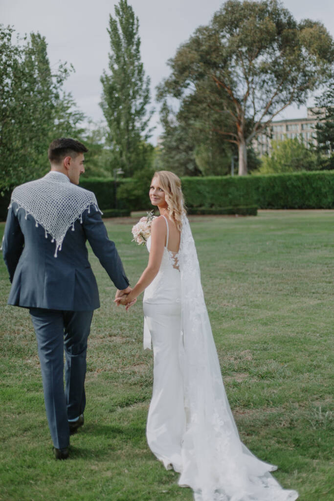 Becky looks back while walking hand in hand with George across Senate Gardens Canberra.