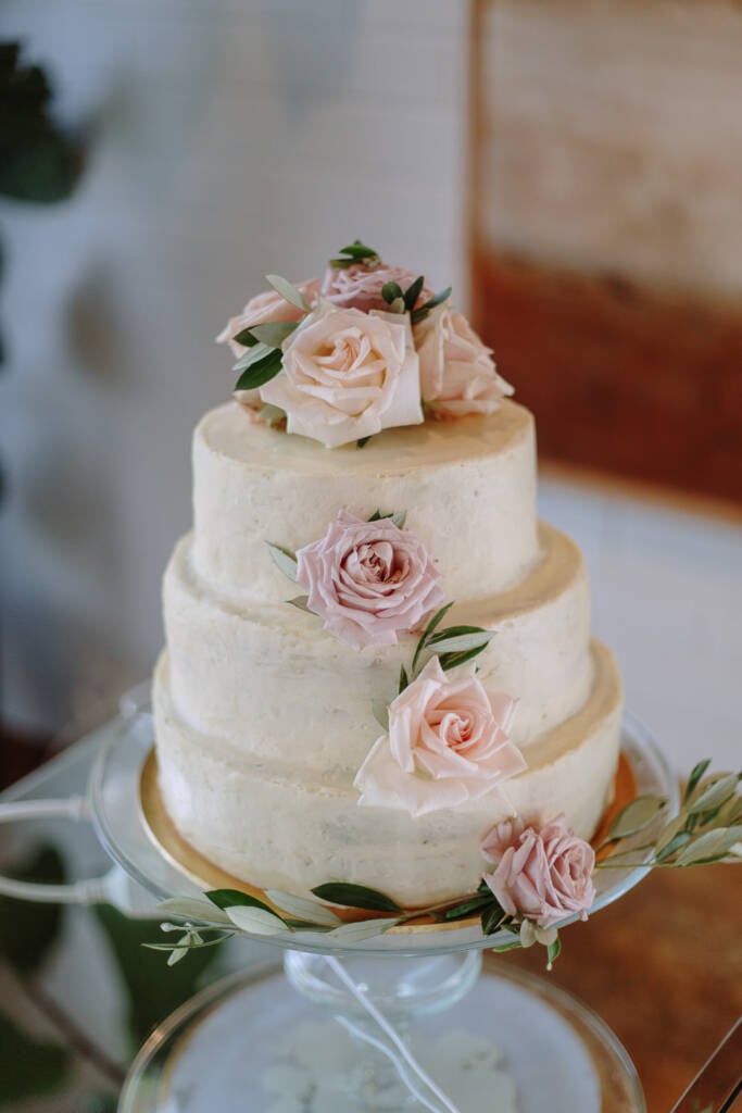 Three-tier white wedding cake with blush roses and foliage at The Boat House Canberra.