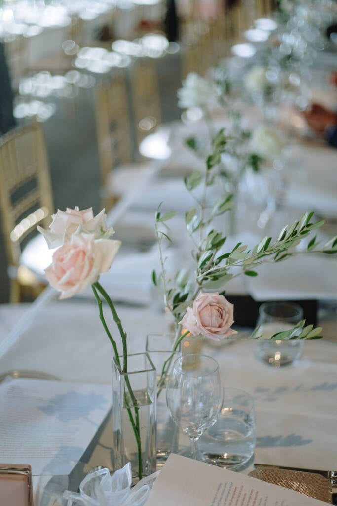 Fine-dining reception table with single-stem flowers and glassware at The Boat House by the Lake.
