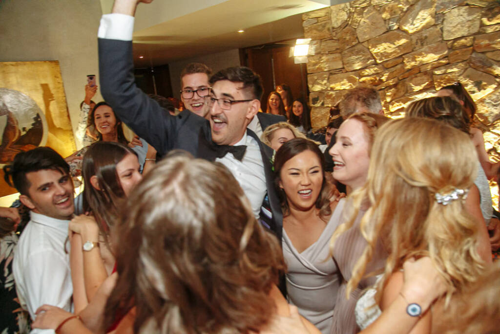 George celebrates shoulder-high above wedding guests during the lively reception.