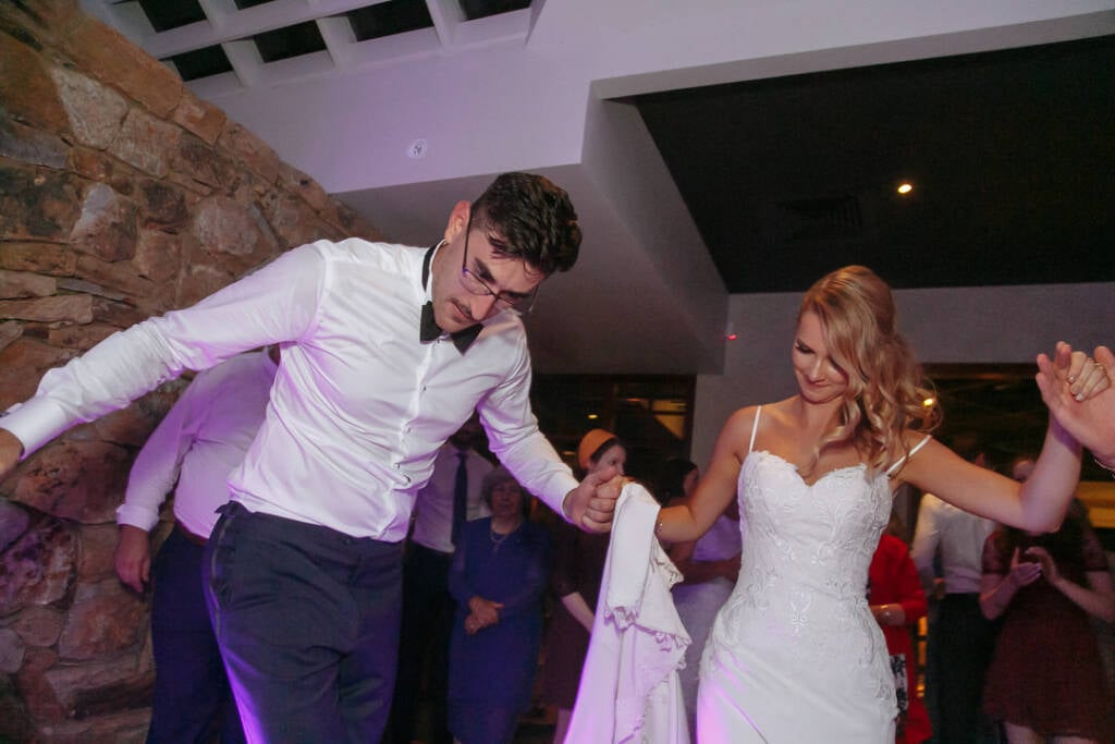 Becky and George dance hand in hand during their Greek islander wedding reception.