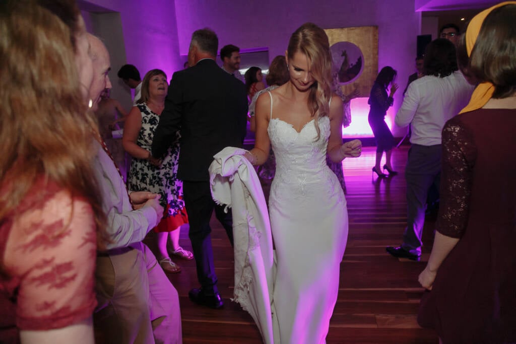 Becky moves through the crowded dance floor with a wrap over one arm.