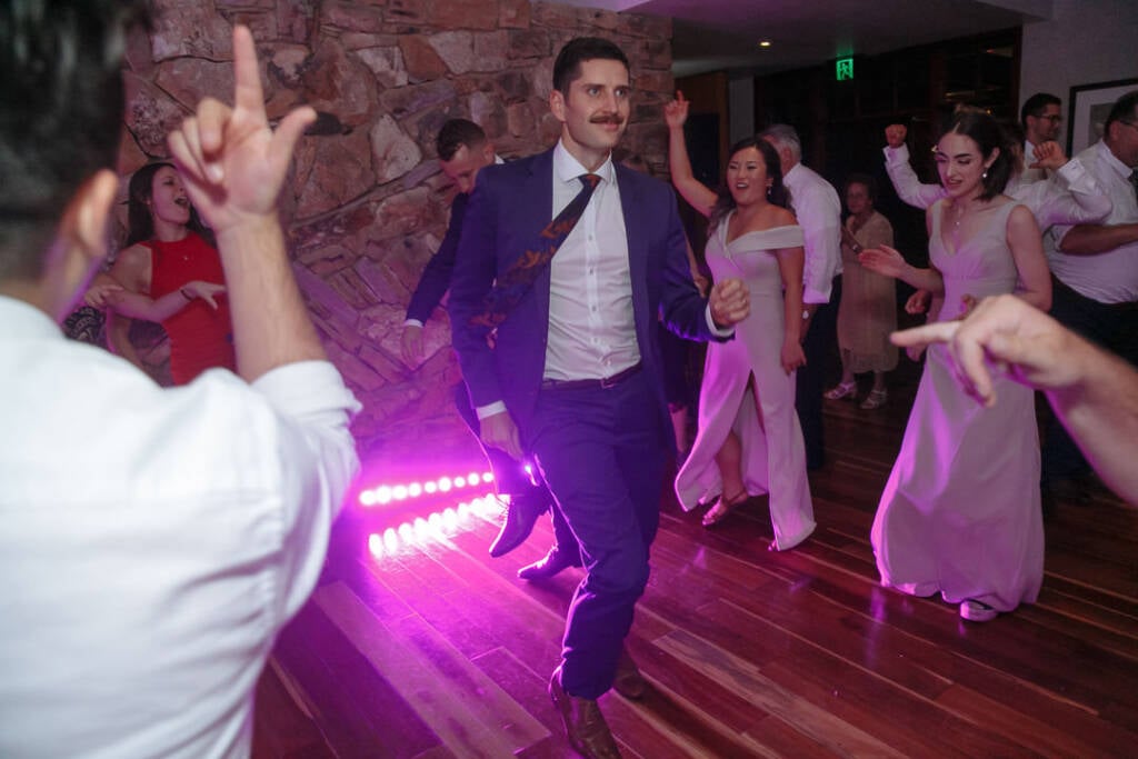 Pink stage light catches George dancing beside the reception steps at The Boat House.