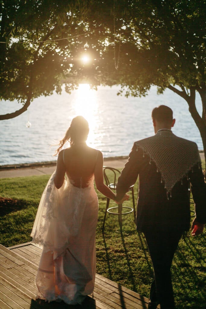 Becky and George walk hand in hand towards the waterfront sunset at The Boat House, Barton.