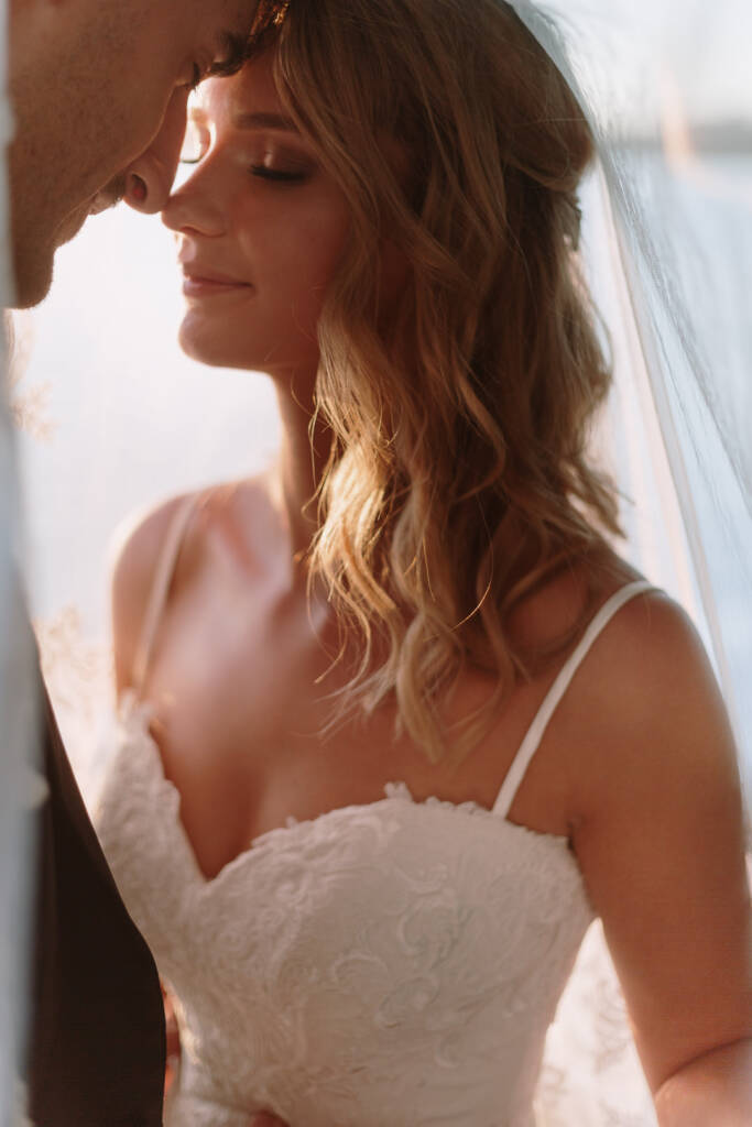 Becky and George share a close portrait beneath her veil in amber sunset light at The Boat House Barton.