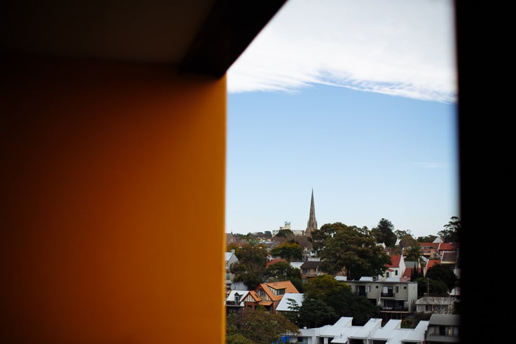 A church spire rises above rooftops and trees in Camperdown, NSW