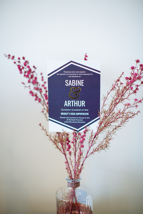 Sabine and Arthur's invitation names Bradleys Head Amphitheatre and Bathers' Pavilion beside pink flowering branches