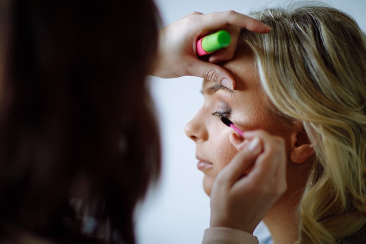 A makeup artist applies mascara to Sabine's eyelashes before the wedding