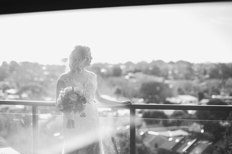 Black-and-white portrait of Sabine holding her bouquet at a balcony railing