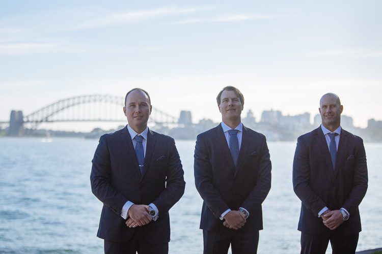 Arthur and two groomsmen stand at Bradleys Head with the Harbour Bridge behind
