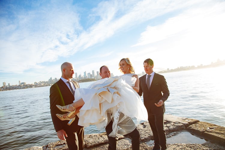 Arthur and two groomsmen carry Sabine beside the water at Bradleys Head