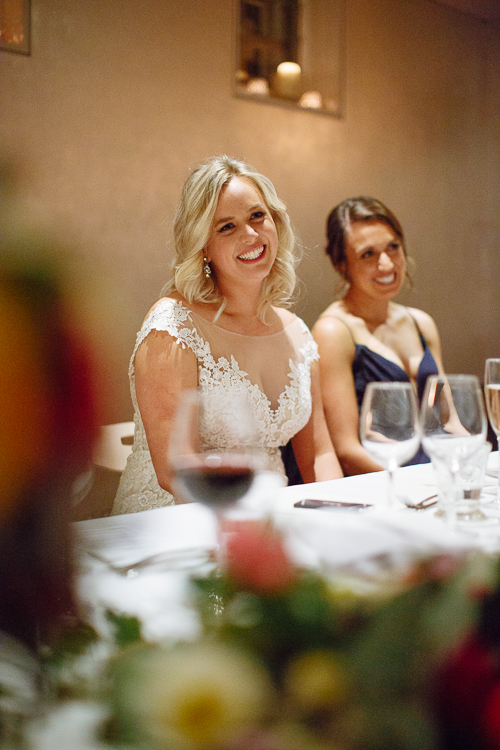 Sabine smiles beside a bridesmaid at the reception table at Bathers' Pavilion