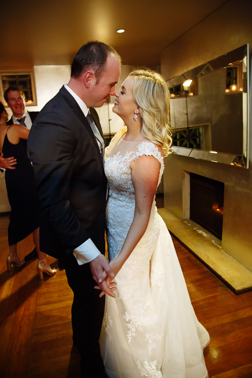Sabine and Arthur stand close beside the fireplace and mirror at Bathers' Pavilion