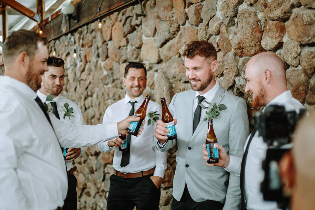 Tory raises a beer bottle with his attendants beside the stone wall at Sunnystones.