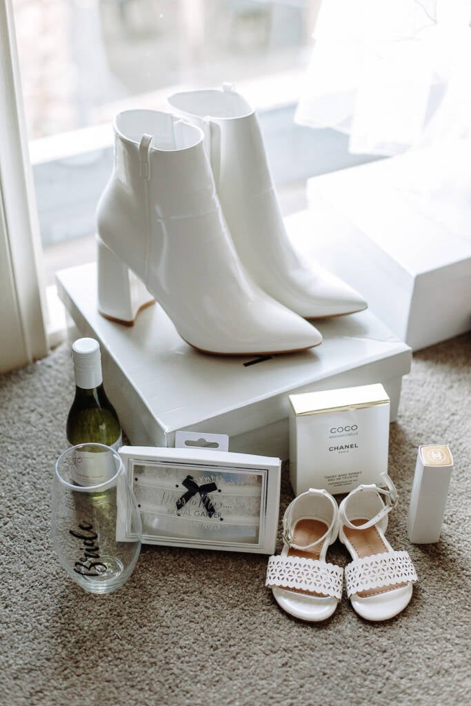 White bridal boots, a boxed garter and small sandals are arranged beside a window.