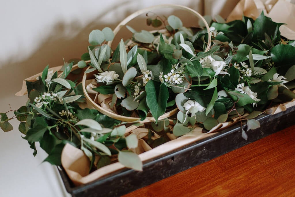 Foliage hoop bouquets rest together in a flower box before the ceremony.