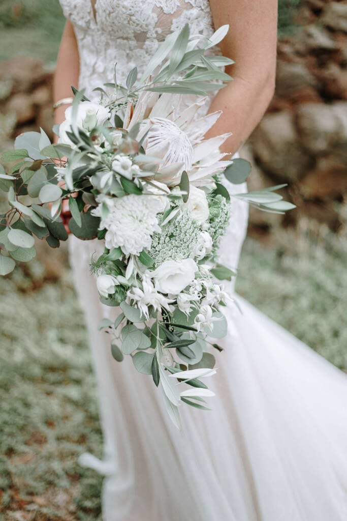 Close-up of Kelly’s white protea bouquet against her wedding gown.