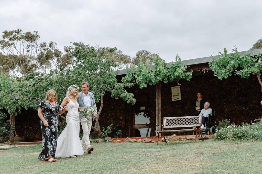 Kelly walks between two guests across the homestead lawn at Sunnystones.