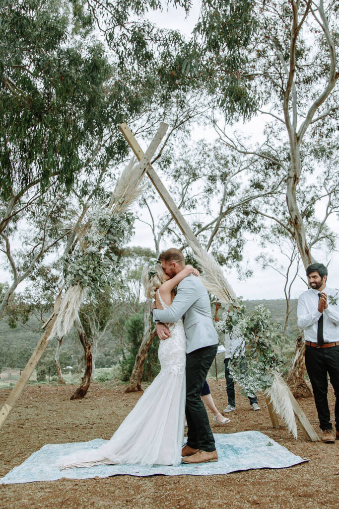 Kelly and Tory kiss beneath the outdoor wedding arbour at Sunnystones.