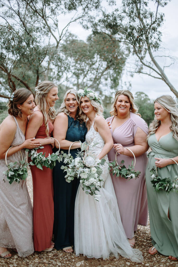 Kelly poses with five attendants holding foliage hoop bouquets at Sunnystones.